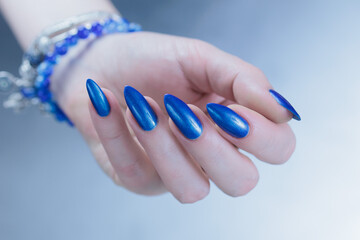 Female hand with long nails and a blue lilac color nail polish