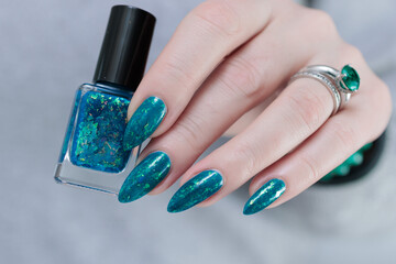Woman hand with long nails and teal blue green manicure