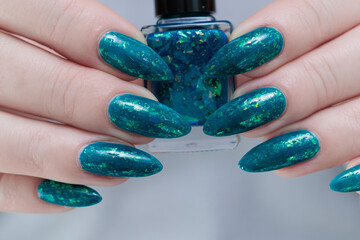 Woman hand with long nails and teal blue green manicure