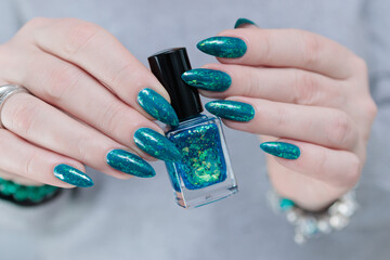 Woman hand with long nails and teal blue green manicure