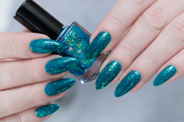 Woman hand with long nails and teal blue green manicure