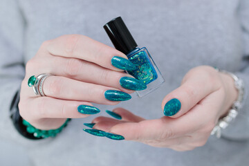 Woman hand with long nails and teal blue green manicure