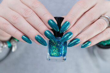 Woman hand with long nails and teal blue green manicure