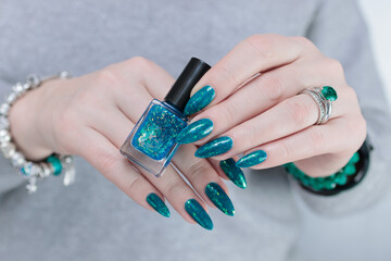 Woman hand with long nails and teal blue green manicure