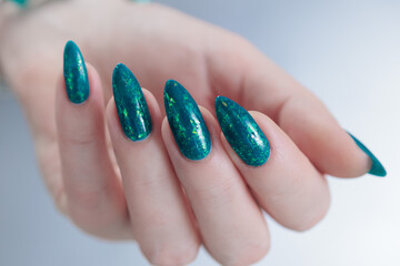 Woman hand with long nails and teal blue green manicure