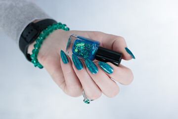Woman hand with long nails and teal blue green manicure