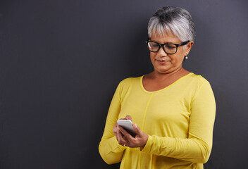 Glasses, phone and senior woman in studio reading text message, email or blog on internet....