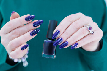 beautiful female hand with long nails and purple blue ink manicure 
