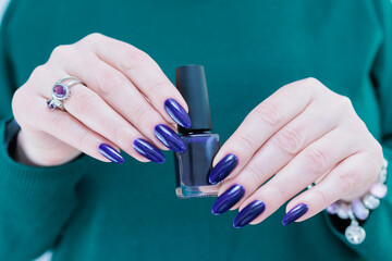beautiful female hand with long nails and purple blue ink manicure 