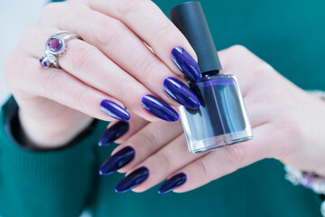beautiful female hand with long nails and purple blue ink manicure 