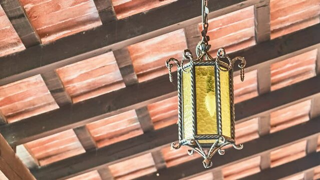 beautiful old lantern swinging in the wind against a wooden roof
