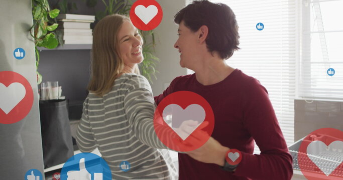 Image of hearts and like icons over caucasian female couple dancing
