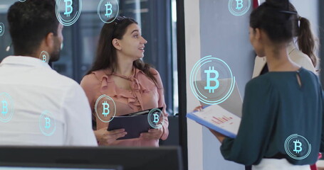 Image of bitcoin symbols over diverse colleagues having meeting in office