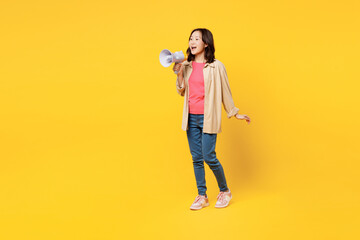 Full body young woman of Asian ethnicity wear pink t-shirt beige shirt casual clothes hold megaphone scream announces discounts sale Hurry up isolated on plain yellow background. Lifestyle portrait. - obrazy, fototapety, plakaty