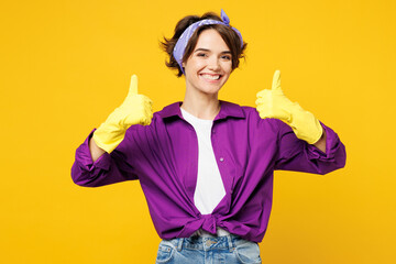 Young smiling happy cheerful woman wear purple shirt rubber gloves while doing housework tidy up...