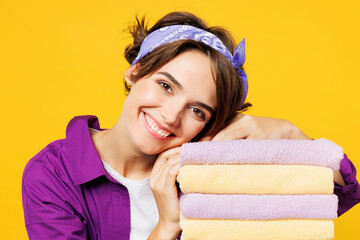 Close up young pensive happy woman wear purple shirt do housework tidy up put head on pile of fresh...