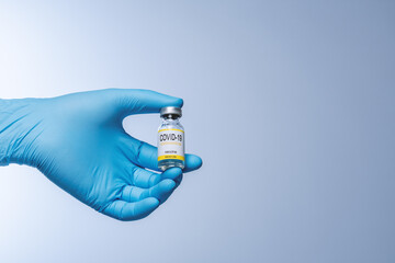 Doctor in blue latex gloves holding glass vial with medicine. Vaccination, immunization, treatment...