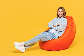 Full body young woman she wears blue shirt white t-shirt casual clothes sit in bag chair hold hands...