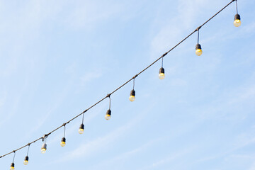 Light bulbs with blue sky,Decorative outdoor string lights hanging on tree in the garden,copy...