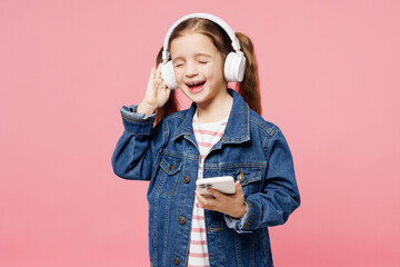 Little child fun kid girl 7-8 years old wear denim shirt listen to music in headphones use mobile...