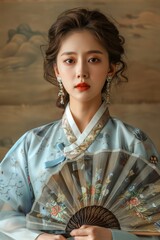 Obraz premium Elegant Asian Woman in Traditional Attire Holding a Decorative Fan Against Artistic Background
