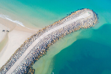 aerial drone top view of a breakwater in a sea of turquoise water