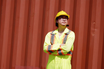 Male engineer wearing safety helmet standing at shipping container.