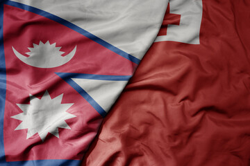 big waving national colorful flag of Tonga and national flag of nepal .