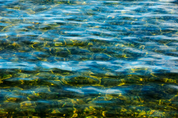 Background of the water of Lake Traunsee in the coastal area. Colorful texture of stones under water.