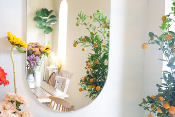 Mirror on blank wall in scandinavian living room interior with flowers in vase on wooden...