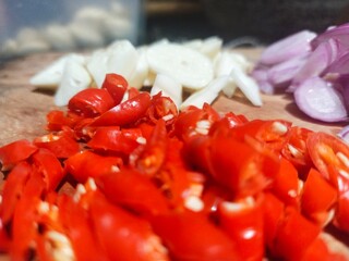 Sliced ​​red chilies, shallots and garlic on a cutting board in preparation for cooking
