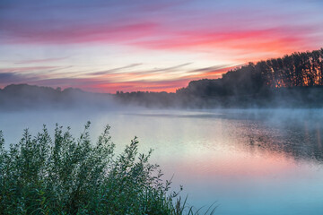 Obraz na płótnie Canvas Dawn landscape on the lake. Early foggy mornings with beautiful skies and clouds. The colors of dawn and fog.