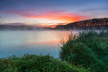 Dawn landscape on the lake. Early foggy mornings with beautiful skies and clouds. The colors of dawn and fog.