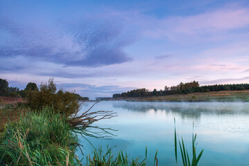 Dawn landscape on the lake. Early foggy mornings with beautiful skies and clouds. The colors of dawn and fog.