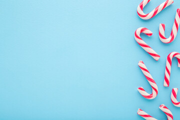 Red white candy canes on light blue table background. Pastel color. Closeup. Sweet food. Empty...