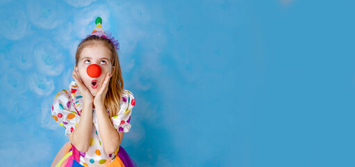Funny kid clown playing against a bright wall. 1 April Fool's day concept, birthday concept. Copy...