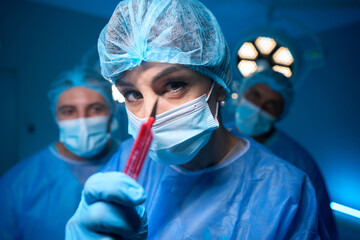 Professional woman surgeon in hospital operating theater showing scalpel