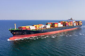 Intermodal container cargo vessel cruising in sea near commercial port. Aerial view