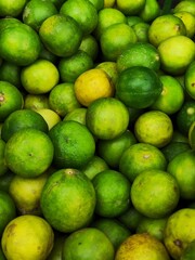 limes piled together on display at a fruit stand in a grocery store