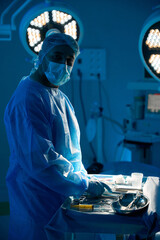 Man surgeon with sterile instruments preparing for surgery in operating room