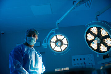 Male surgeon standing in operation theater at hospital preparing for operation