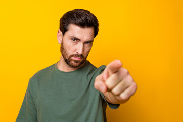 Photo of serious confident man wear khaki t-shirt pointing finger you empty space isolated yellow...