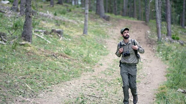 Young explorer man walking in the forest. Park ranger hiking in the woods.
