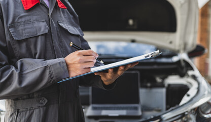 Services car engine machine, Automobile mechanic repairman checking a car engine with inspecting writing to the clipboard the checklist for repair machine, car service and maintenance. - obrazy, fototapety, plakaty