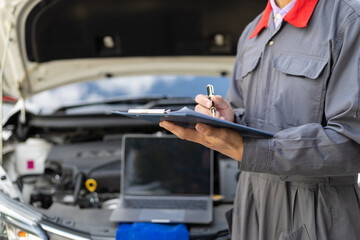 Services car engine machine, Automobile mechanic repairman checking a car engine with inspecting writing to the clipboard the checklist for repair machine, car service and maintenance.
