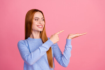 Portrait of satisfied girl with foxy hair wear blue pullover look directing at offer on palm empty...