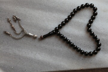Prayer beads made of Erzurum Oltu Stone. Black and silver prayer beads on the gray marble floor.