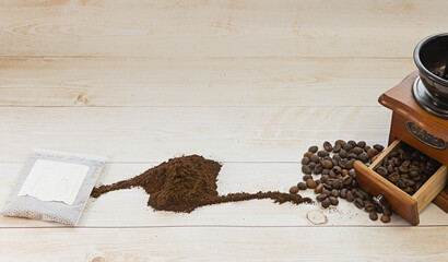 Filter bag with ground coffee, manual coffee grinder and cup of espresso coffee on a white isolated background. Copy space