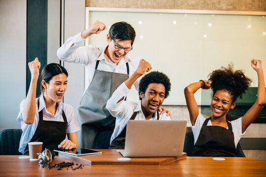 Stylish coffee shop diverse entrepreneurs hold team meeting. Barista owner discuss work on laptop. Multiethnic employees successful teamwork business strategy discussion.