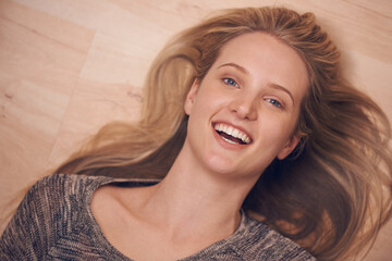 Happy, portrait and woman on a floor with confidence, positive attitude or feel good mood from above. Face, smile and female person relax in a living room on day off, weekend or vacation in her home